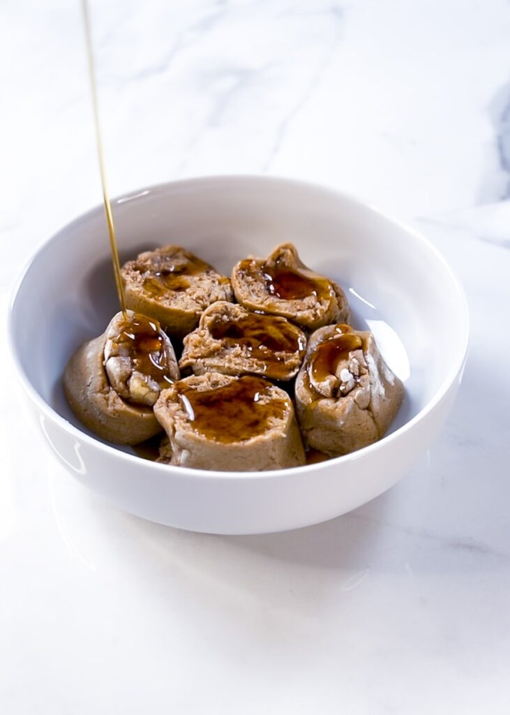 Maple syrup drizzled on cinnamon rolls.