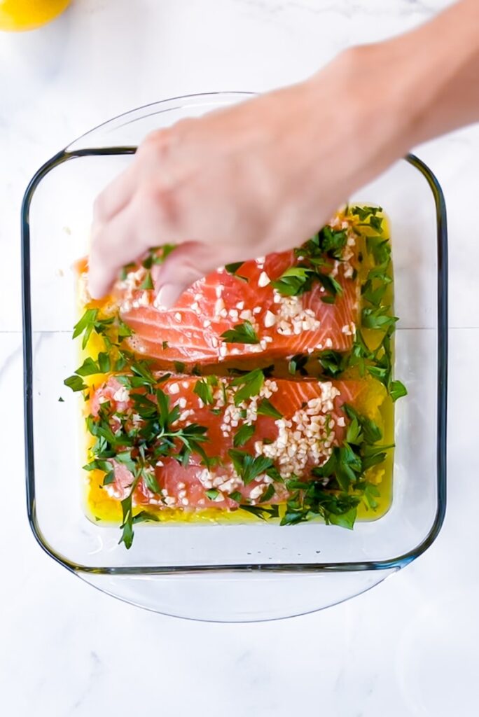 Hand putting herbs in dish.